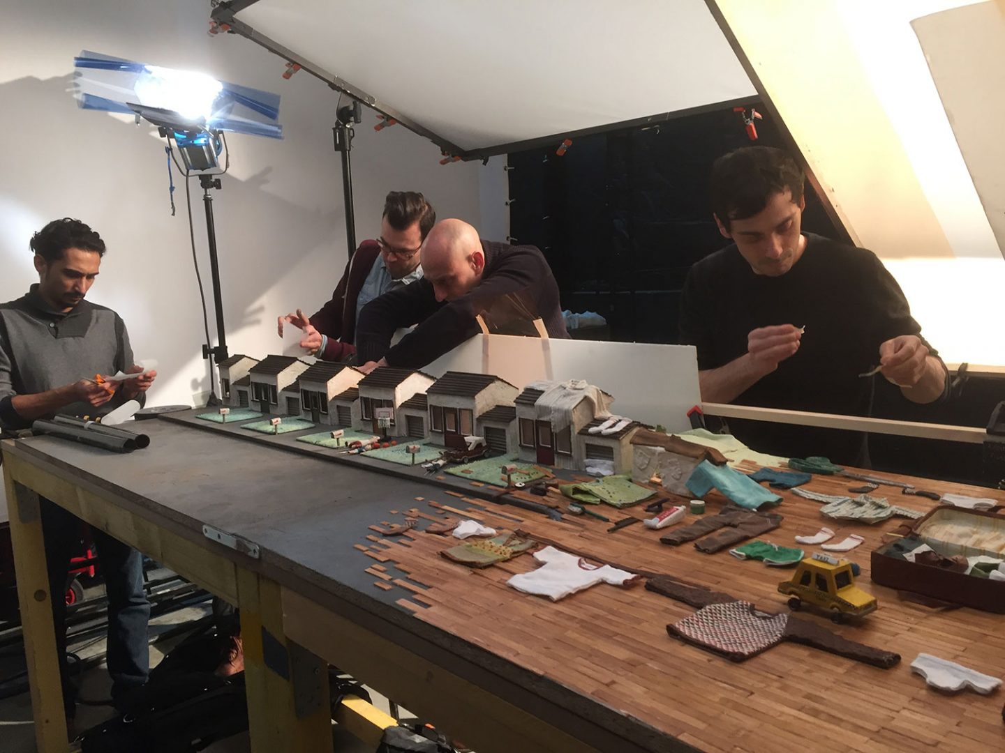 One of the largest sets - the pan of suburb - being lit. The team is using gels and gaffer tape to control small lighting details. From left: Walid Païenda (production assistant). Simon Gesrel (cinematographer), Jean-Louis Padis (co-producer), and Max Porter (co-director).